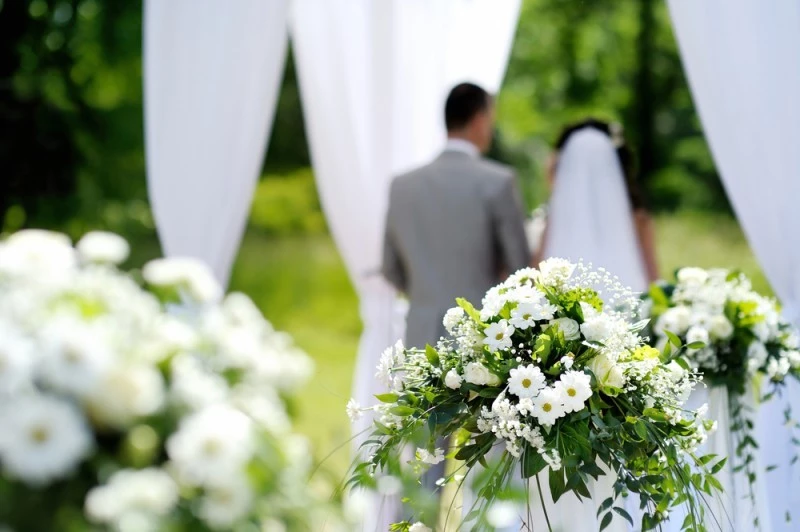Casal no altar, com flores brancas ao redor. 