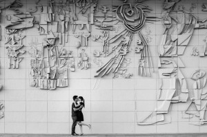 Casal tirando fotos pré-wedding em um paredão urbano.