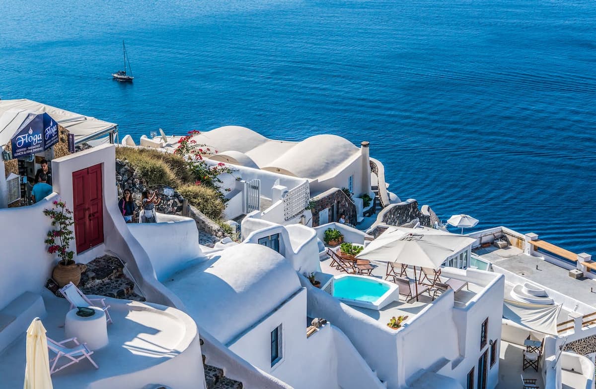 Imagem de casas brancas com uma piscina na frente de um mar azul