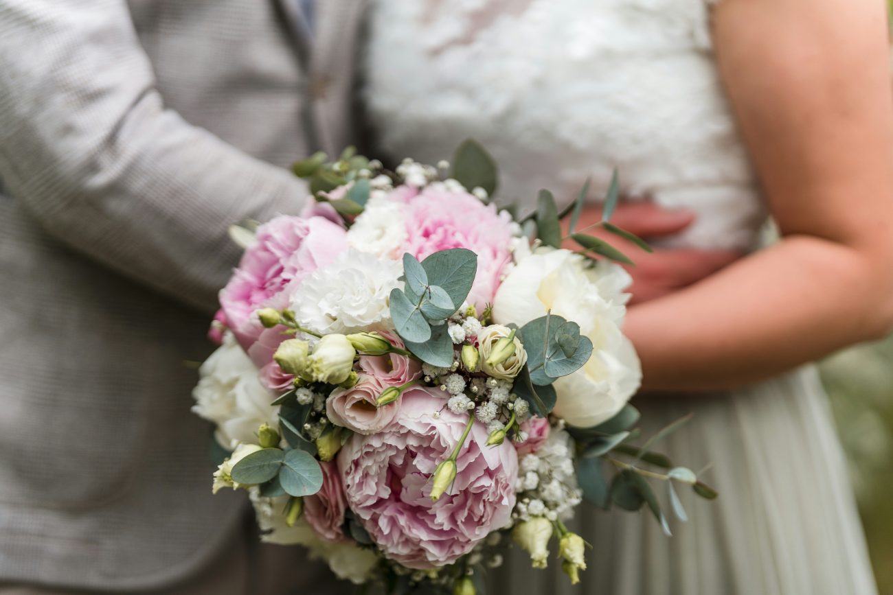 casal de noivos segurando buquê de flores rosas e brancas