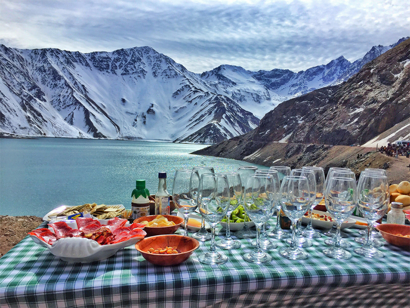 Mesa com taças e comidas montada entre montanhas no Chile. 