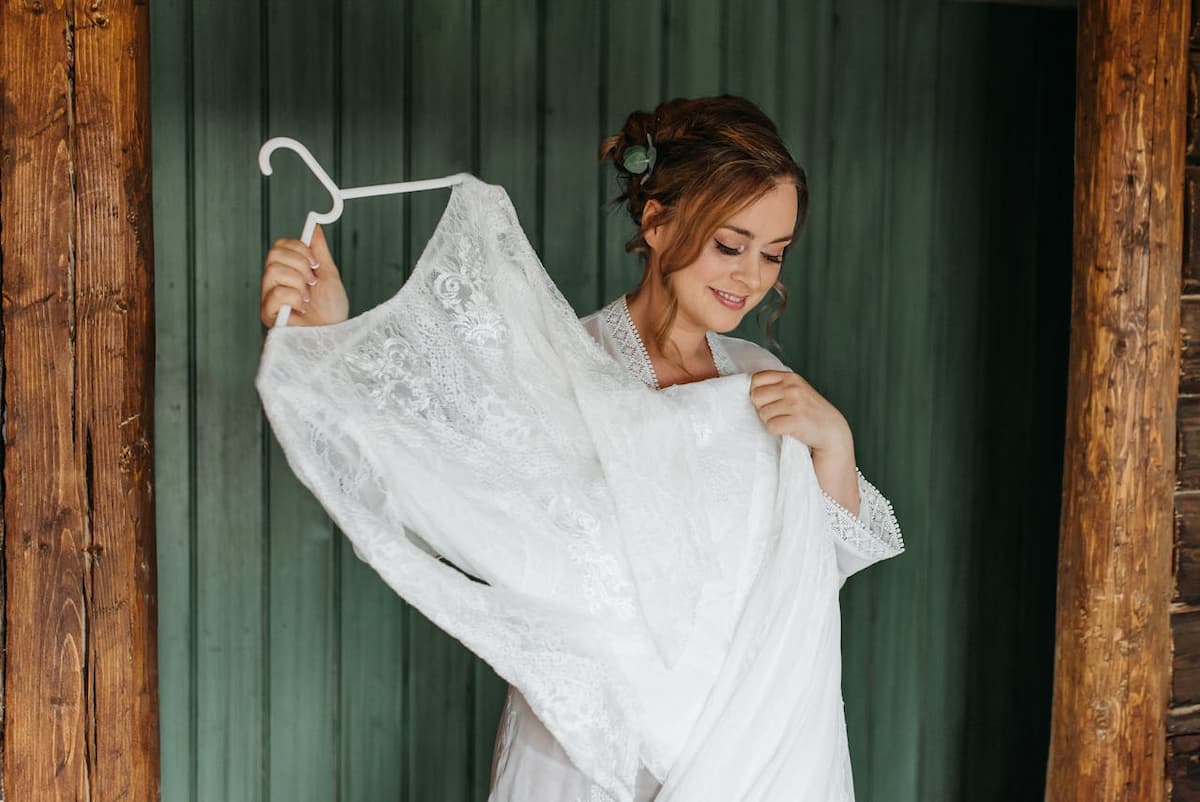 Imagem de uma mulher segurando o seu vestido de noiva no cabide