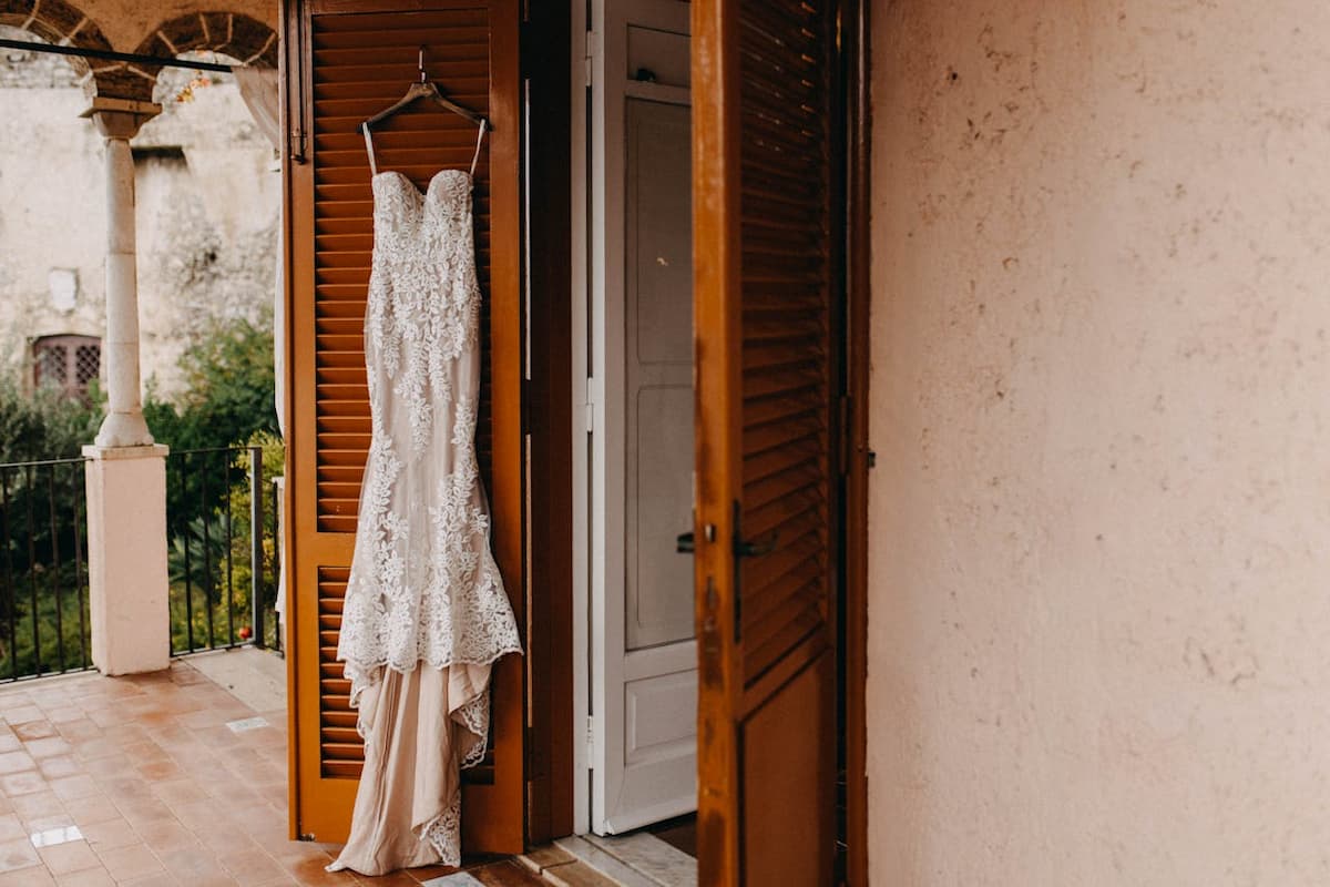 Imagem de um vestido de noiva pendurado na porta de madeira