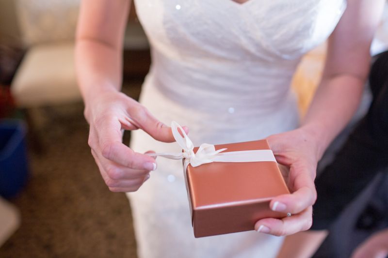 Foto das mãos de uma noiva abrindo um presente de casamento 