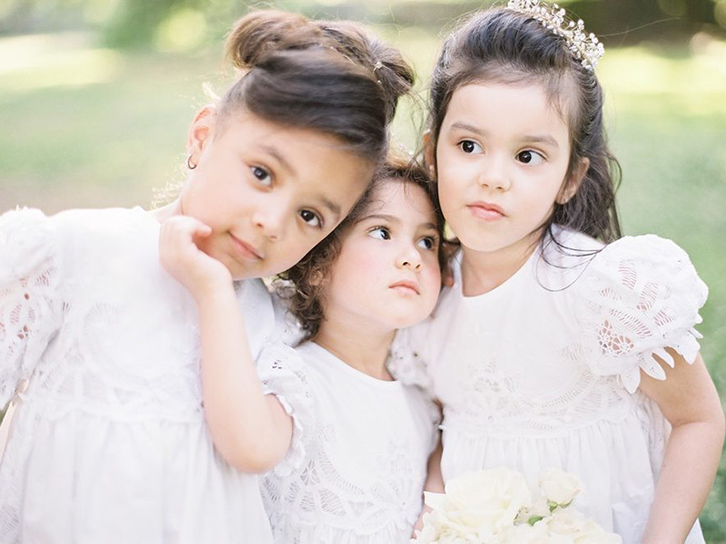 Três meninas vestidas de daminhas de casamento.