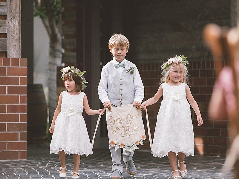 Um menino e duas meninas entrando no casamento anunciando a chegada da noiva.