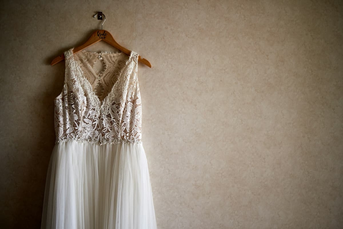 Imagem de um vestido de renda branco pendurado na parede