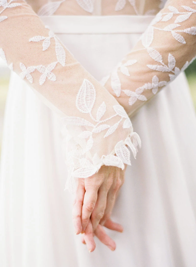 Mãos entrelaçadas de uma mulher vestida de noiva.