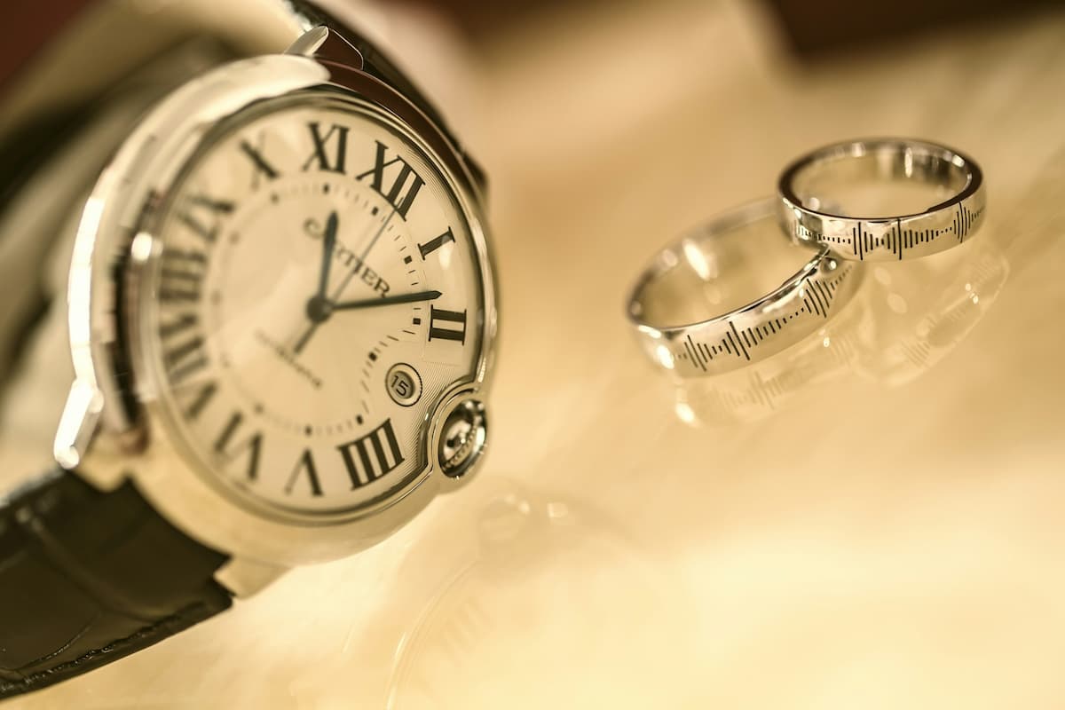 Imagem de dois anéis personalizados ao lado de um relógio prata