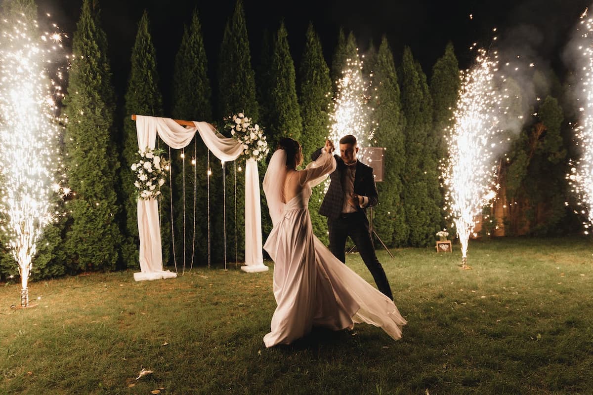 Imagem de um casal dançando no gramado do casamento com luzes atrás