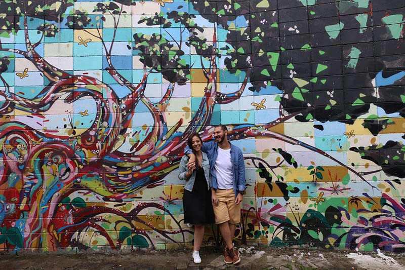 Casal posando na frente de uma parede artística