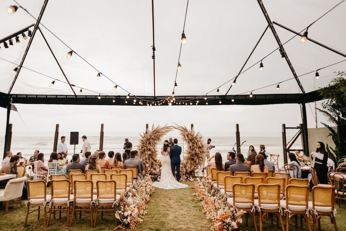 Imagem de um casamento na luz do dia com os noivos se casando no meio 