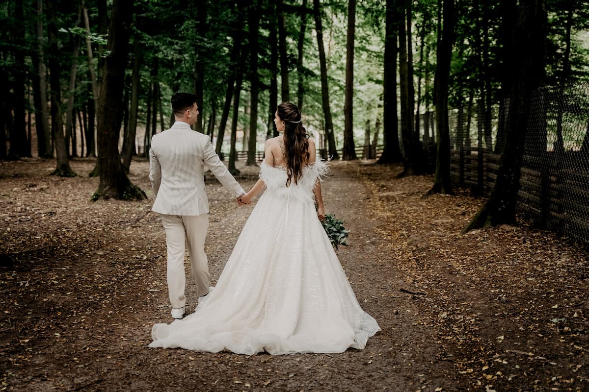 Homem e mulher vestidos de noivos andando em uma floresta