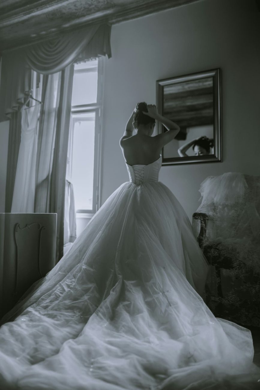 Uma noiva mexendo em seu coque, com um vestido estilo princesa