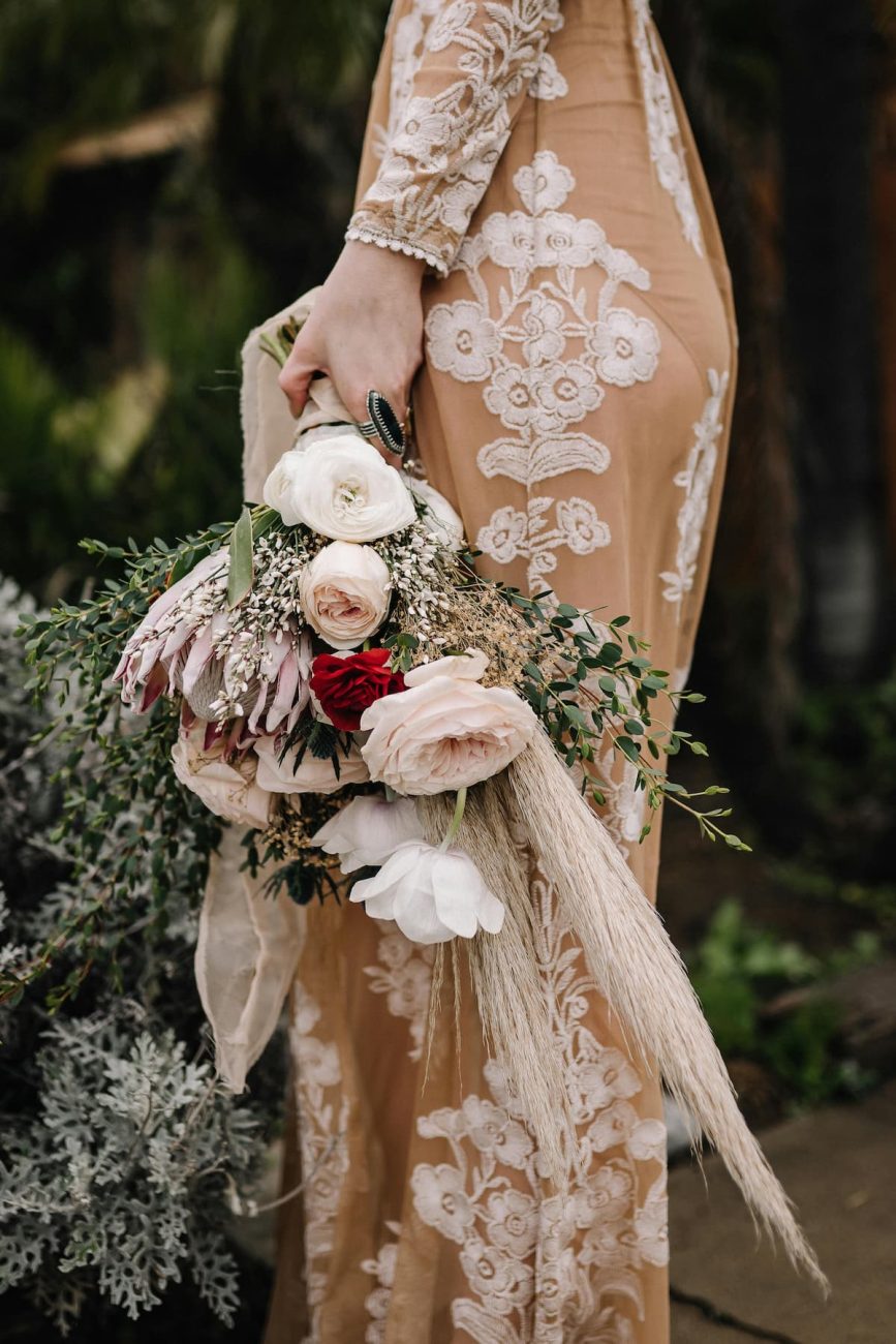 Uma noiva segurando seu buquê e com um vestido bordado personalizado 