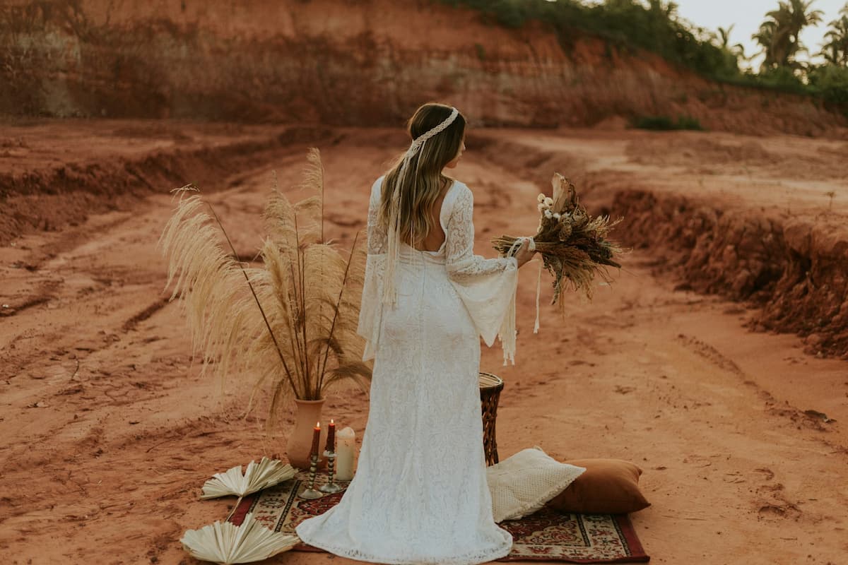 Imagem de noiva com vestido com mangas em capa em um deserto