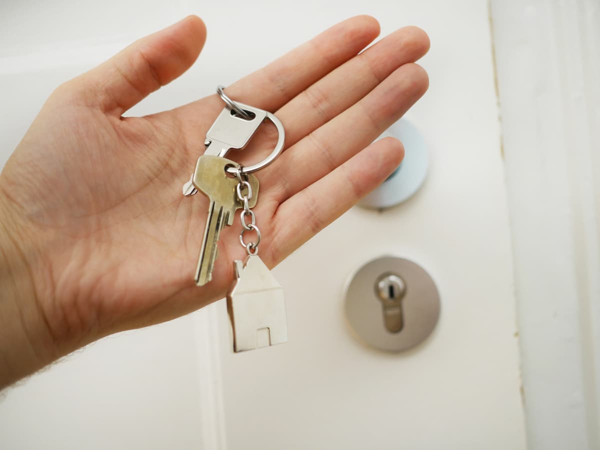 Imagem de um mão com uma chave na frente da porta