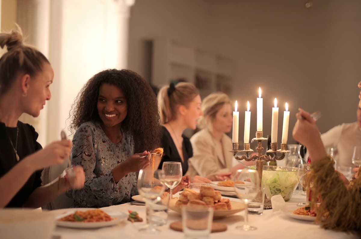 Imagem de amigas jantando em casa com uma mesa com velas