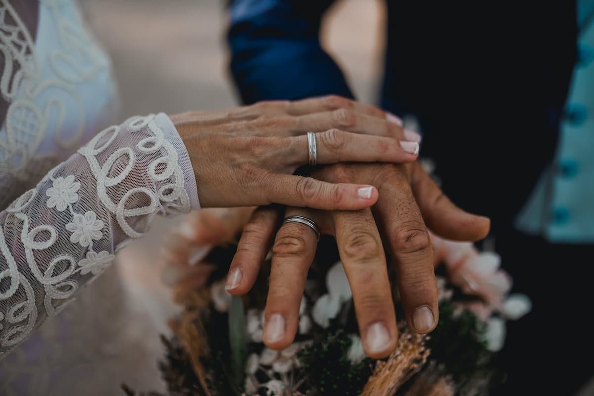 Imagem da mão de duas pessoas se casando mostrando os anéis