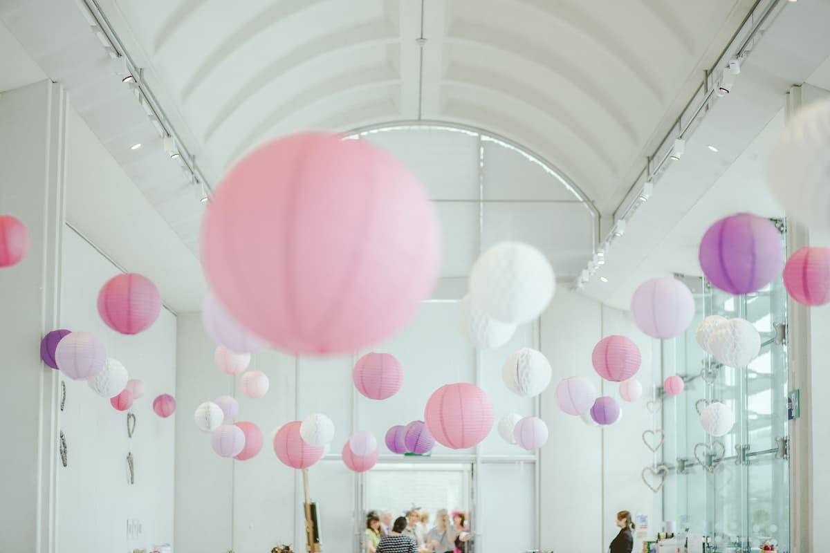 Diversos balões de decoração no teto de cor rosa, roxo e branco