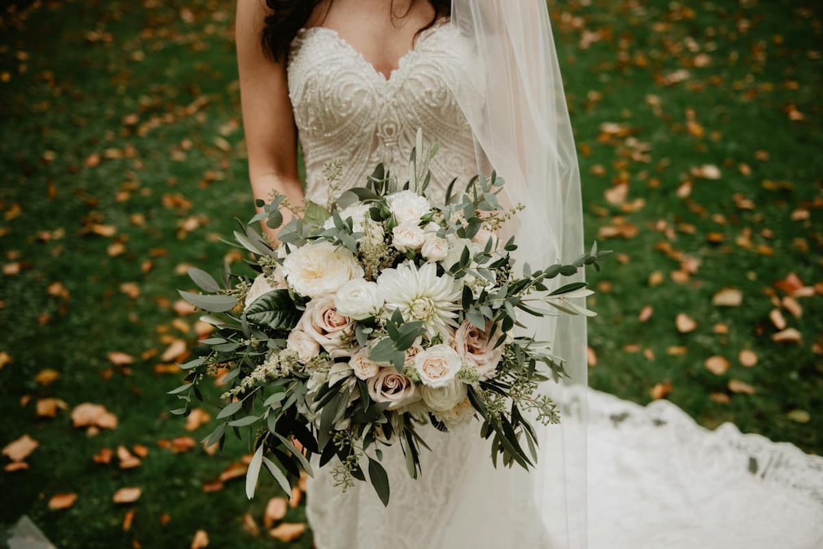 Mulher com vestido de noiva segurando um buquê