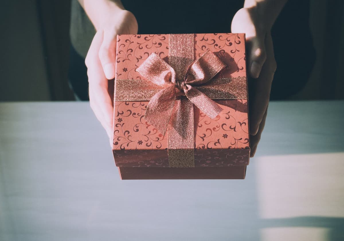 Imagem de uma pessoa entregando uma caixa de presente vermelha para alguém