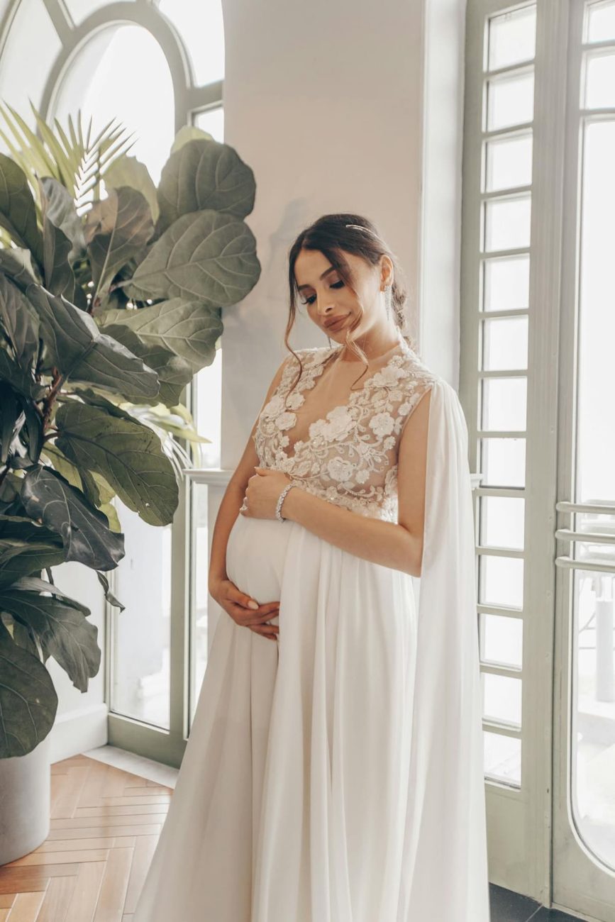 Imagem de uma mulher grávida usando um vestido de noiva de renda