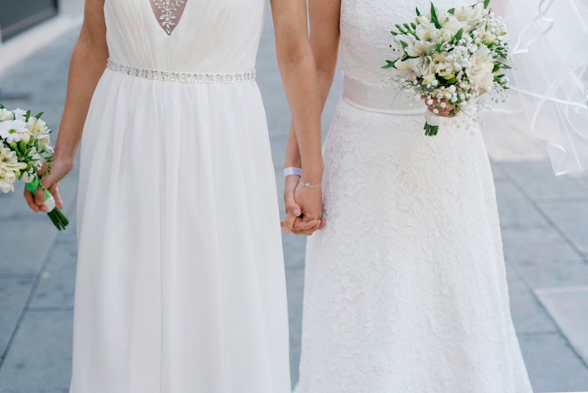 Imagem de duas mulheres de mãos dadas com vestido de noiva