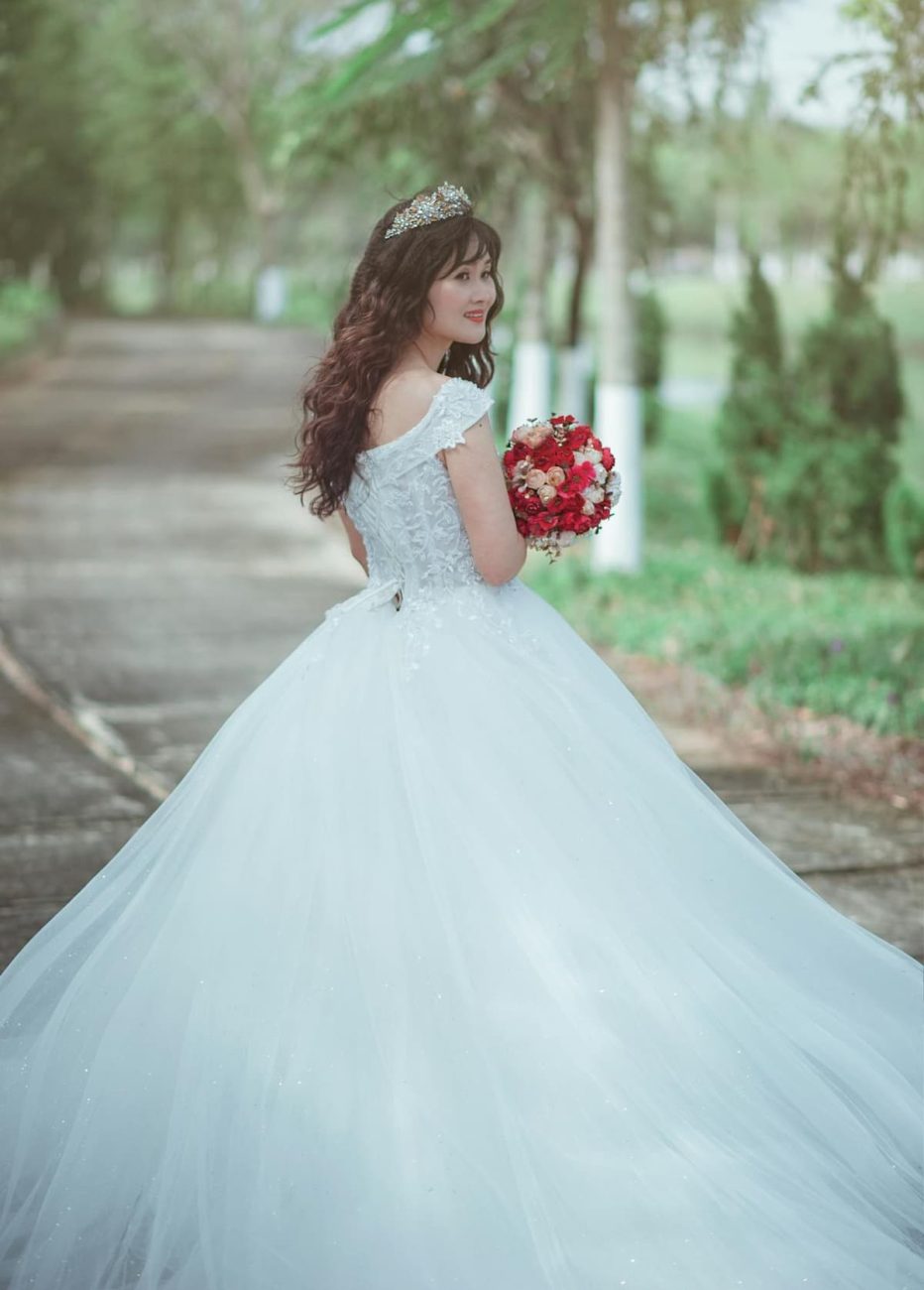 Imagem de uma noiva com vestido de princesa segurando um buquê vermelho