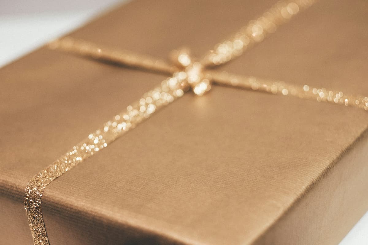Imagem de um presente com embrulho dourado e laço com brilhos