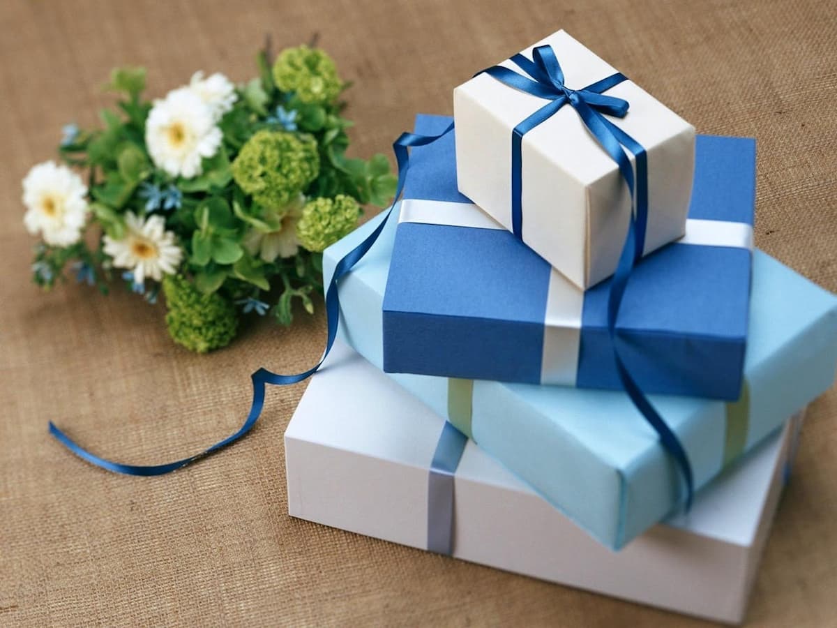 Imagem de caixas de presente com papel azul com uma flor ao lado