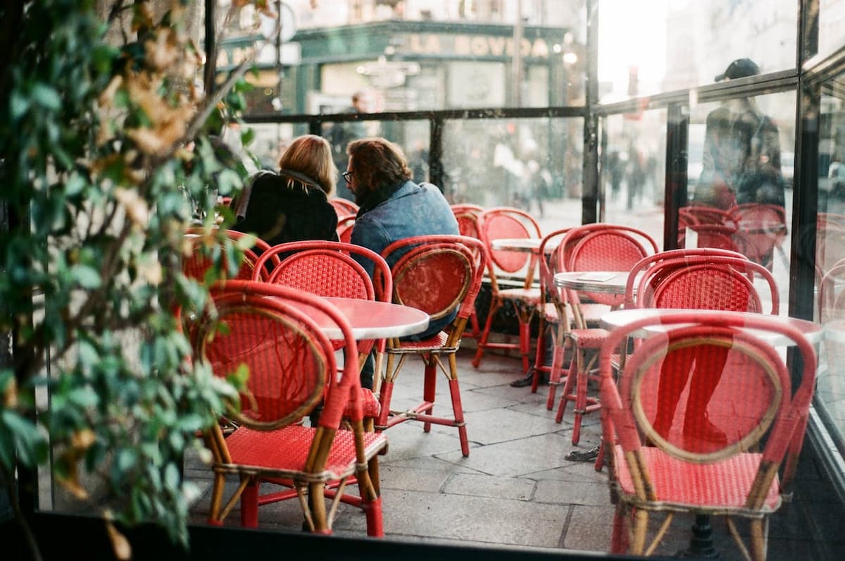 Imagem de um casal sentado em um restaurante com cadeiras vermelhas