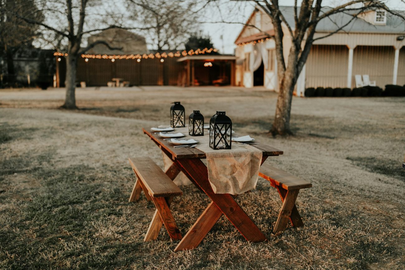 Detalhe de decoração para casamento na fazenda com mesa em madeira, gramado e ao ar livre