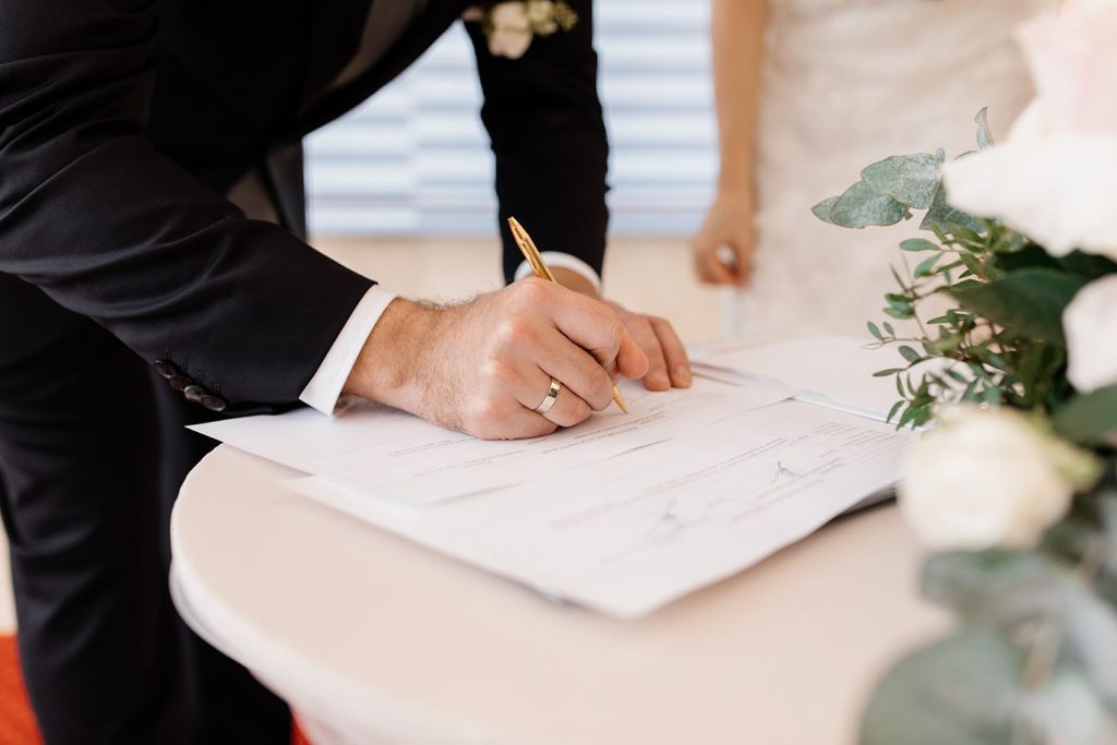 Homem de terno assinando casamento no civil.