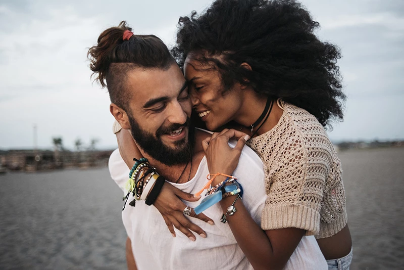 Casal se abraça na beira de uma praia. 