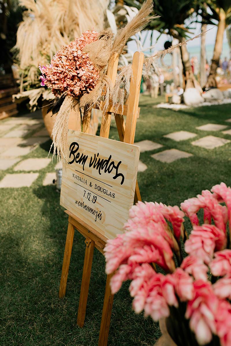 Decoração com flores rosadas e folhagens na cerimônia na praia
