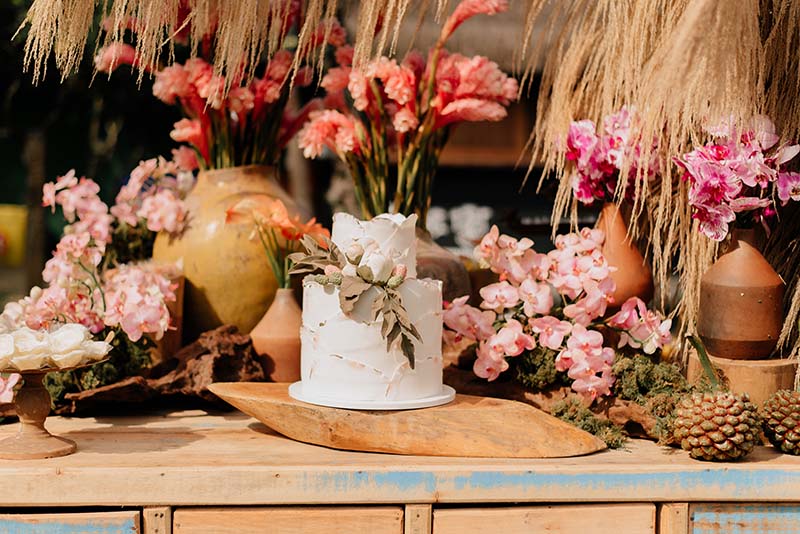 Mesa comunitária com composição rústica e flores rosadas