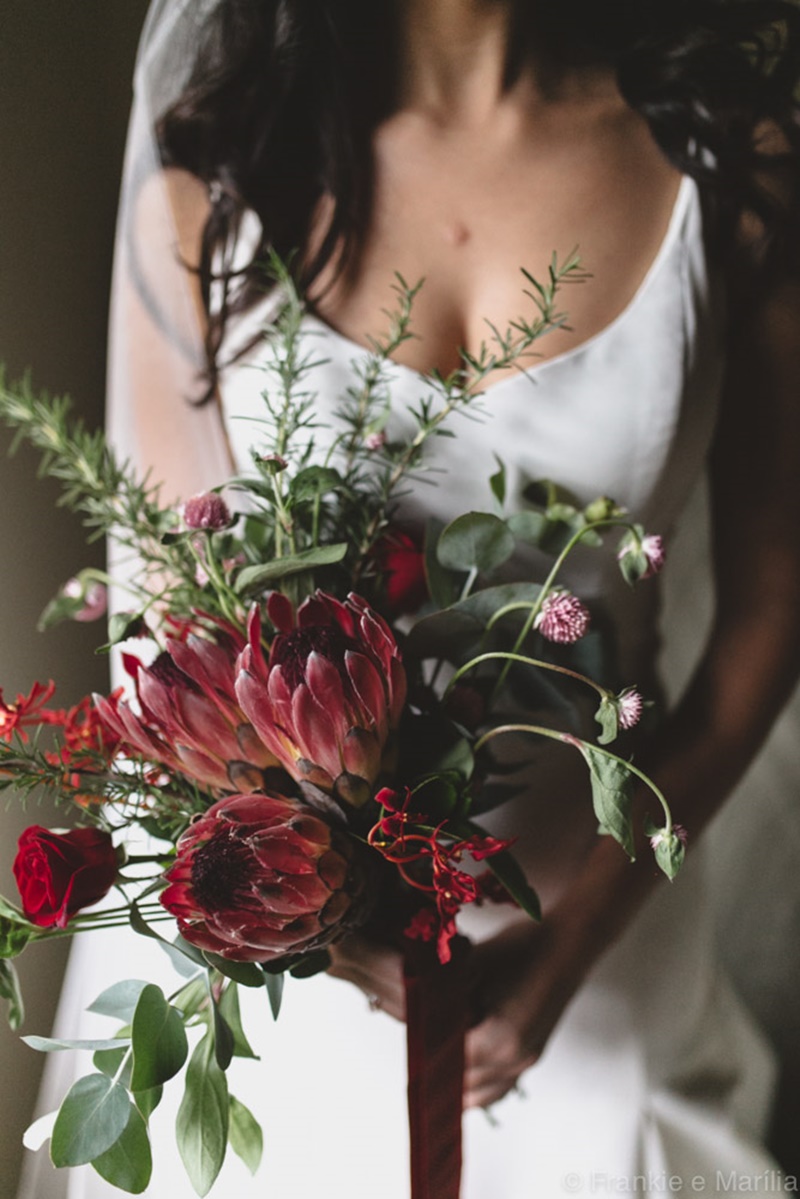 Noiva segurando um buquê de noiva diferenciado em formato desconstruído e cores vibrantes, com fita longa