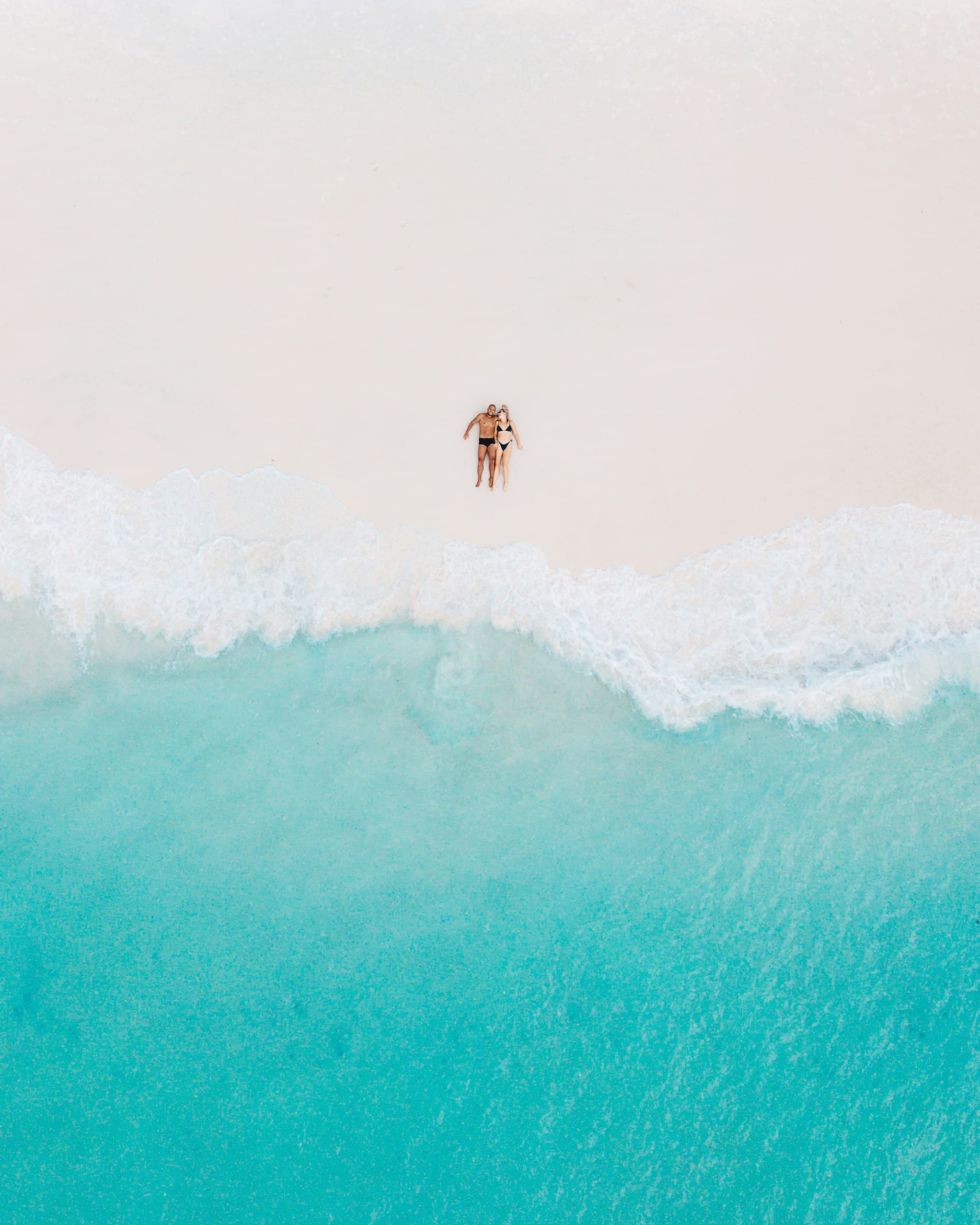noivos deitados na praia durante a lua de mel