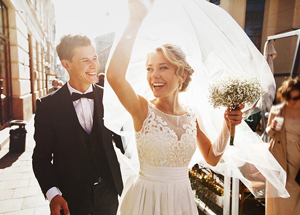 |um homem e uma mulher celebrando a festa de casamento|uma mulher sentada no sofá e um homen deitado no colo dela segurando um controle|um homem e uma mulher dançando felizes na cozinha|