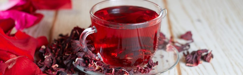 cha-de-hibisco|dois-copos-com-chá-de-hibisco-gelado|chá-de-hibisco-com-canela-em-xícara-portuguesa|mulher-coando-chá-de-hibisco|chá-de-hibisco-gelado|chá-de-hibisco-em-formato-de-sorvete|