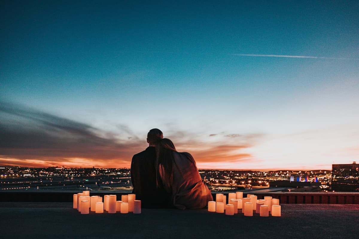 Casal na praia em um pôr do sol com várias velas na areia|Casal no restaurante demonstrando carinho|Anel de casamento dentro de um doce|Casal apoiado no coqueiro na frente da praia no pôr do sol|Casal sentado na mesa com itens decorativos românticos|Casal deitado na praia bebendo vinho|Casal se beijando em uma sala de cinema|Casal em um restaurante jantando com velas e vinho|Mulher segurando uma carta com um coração dentro|Mulher preparando um presente com corações
