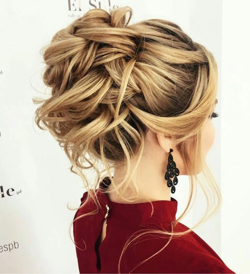 Madrinha de casamento de cabelos claros exibe penteado de coque baixo.