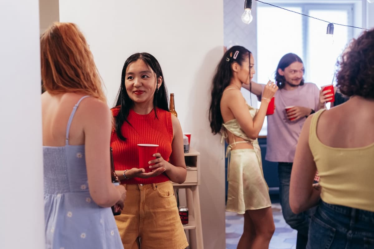 Amigos conversando em uma festa em casa|Amigos em uma festa em casa com um homem ganhando um presente de uma mulher|