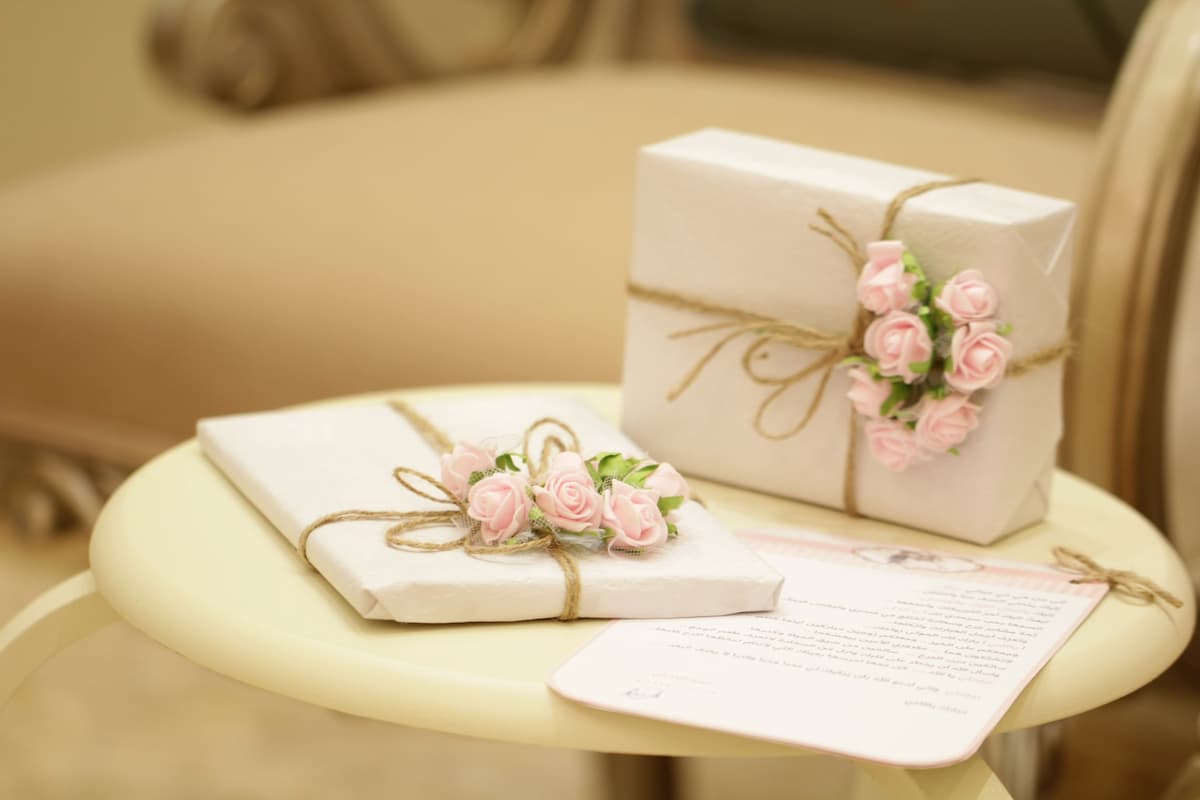 Imagem de presentes de casamento com decoração branca e flores|Imagem de uma toalha de massagem|Imagem de objetos de piquenique|Imagem de um casal em um jantar romântico|Imagem de queijos e vinho em uma mesa branca