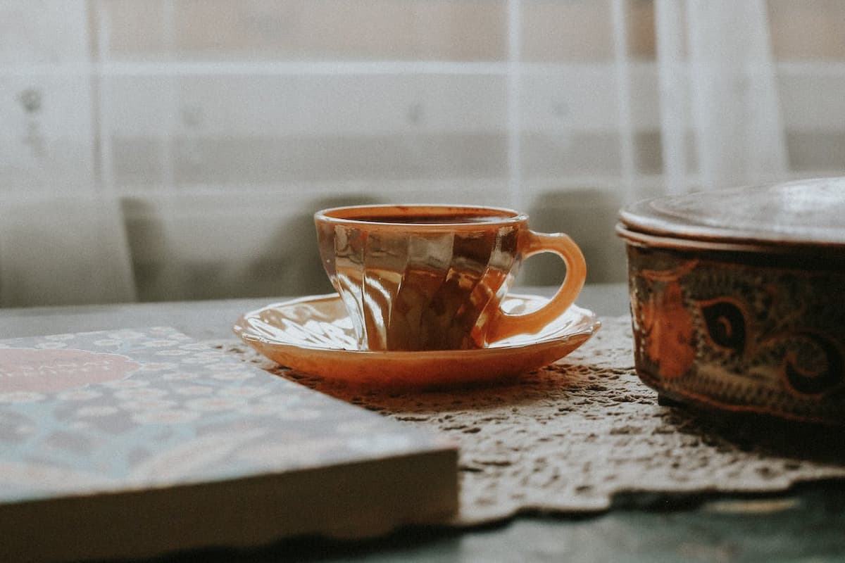 Xícara de chá dourada do lado de livro 