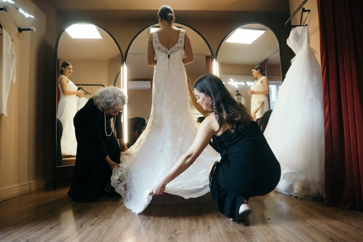 Imagem de uma mulher experimentando o vestido de noiva na loja com as vendedoras a ajudando|Linha do tempo para o look da noiva no casamento|||Linha do tempo para o look da noiva no casamento|Linha do tempo para o look da noiva no casamento||Linha do tempo para o look da noiva no casamento|Linha do tempo para o look da noiva no casamento|||Linha do tempo para o look da noiva no casamento|Linha do tempo para o look da noiva no casamento||Linha do tempo para o look da noiva no casamento|Linha do tempo para o look da noiva no casamento||look da noiva||vestido de noiva|vestido de noiva|vestido de noiva|vestido de noiva|vestido de noiva|vestido de noiva|vestido de noiva|vestido de noiva|vestido de noiva|vestido de noiva|Imagem de um vestido de noiva pendurado na porta de madeira|Imagem de uma mulher segurando o seu vestido de noiva no cabide|Imagem do pescoço e colo de uma mulher com o vestido de noiva